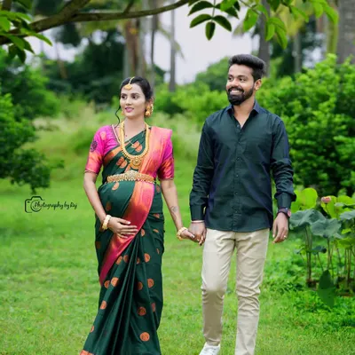 A beautiful couple's portrait taken during a walk in our garden. The mother-to-be looks stunning in a dark green and pink silk saree, complemented by traditional gold jewelry.