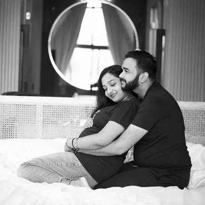 This black and white photo captures a tender moment between a couple during their indoor maternity session. The focus is purely on their connection and the gentle embrace, creating a timeless and emotional portrait.