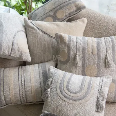 A pile of cushions from our Contours Collection, showcasing a variety of geometric designs. The soft, soothing palette and refined detailing bring sophistication to a neutral-toned sofa.