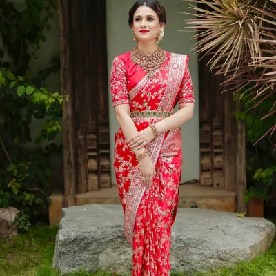 A full-length view of the pure red Katan silk Banarasi saree. The intricate handwoven floral pattern and the matching embroidered blouse create a look of unparalleled bridal grandeur.