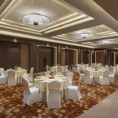 This banquet hall at the DoubleTree by Hilton in Jaipur is designed for versatility. The lighting scheme uses elegant cove lighting within the coffered ceilings to provide soft, indirect ambient light, supplemented by large decorative fixtures that add a touch of formality and scale.