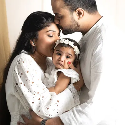 A beautiful family embrace, with parents showering their little one with love. This is a classic family portrait that shows the warmth and protection that surrounds a child.