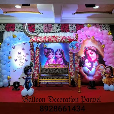 A grand stage decoration for a 'Dohale Jevan' or baby shower in a hall. The setup features a beautiful cradle, traditional backdrops, and balloon arches in pink and blue.