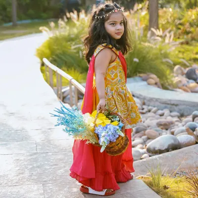 A little princess in a beautiful garden, holding a basket of flowers. The soft, natural light and serene path create a fairytale-like setting for this outdoor portrait.