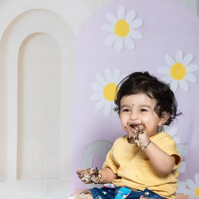 The pure joy of a first birthday cake smash! This little one is having the best time, with cake all over his hands and face.