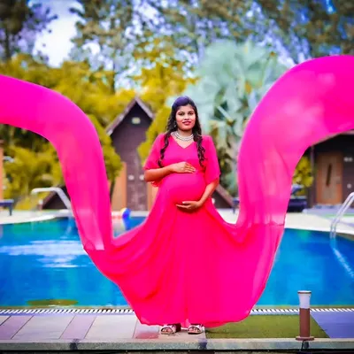 This vibrant pink flying gown is perfect for a poolside maternity shoot. The long, flowing fabric creates a beautiful effect in photos, making it one of my most popular maternity dress rentals in Bangalore.
