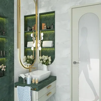 We designed this modern wash basin area with a bold green marble-look tile. The oval mirror with integrated lighting and the floating vanity with built-in niches create a space that is both functional and aesthetically pleasing.