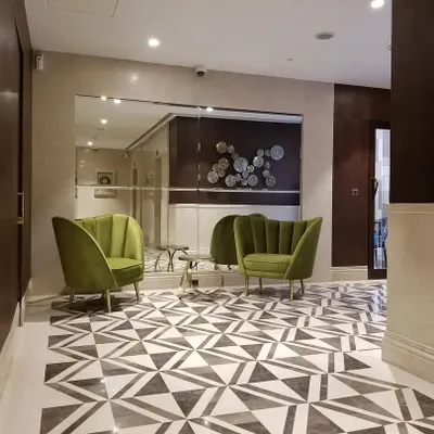 This is the lift lobby at our Bellevue project. I used a striking geometric pattern on the floor with contrasting marbles to create a dynamic visual effect. The plush olive green chairs add a pop of color and a touch of modern elegance.