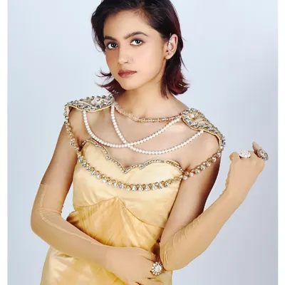 This portrait highlights a beautiful pearl and crystal-embellished bodice on a golden gown. The soft, high-key lighting creates a dreamy and ethereal feel, perfect for showcasing delicate designer work.