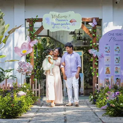 A family portrait at a beautiful fairy-garden-themed first birthday party. The personalized entrance and milestone board add a lovely, sentimental touch to the celebration.