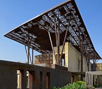 The Tree House in Delhi is defined by its massive, sheltering roof canopy, which is supported by columns that branch out like trees. This award-winning project is a bold statement on integrating natural forms into contemporary urban architecture.