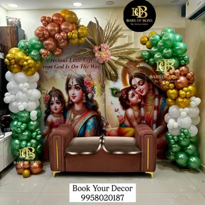 A divine Radha Krishna themed backdrop for a traditional baby shower. The beautiful printed backdrop is framed by an arch of green, white, and gold balloons, creating a blessed and serene atmosphere.