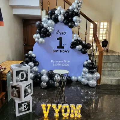 A stylish and modern setup for a first birthday. The black and silver chrome balloons with a simple lavender backdrop create a chic look for this important milestone.