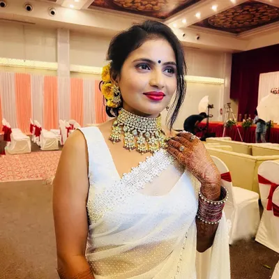 My client was the star of her sister's reception in this stunning white saree. I created a glamorous look with a purple smokey eye, a bold red lip, and a chic floral bun.