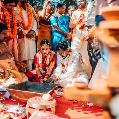 A candid moment from a traditional South Indian wedding ceremony, with the couple surrounded by their family and vibrant rituals.