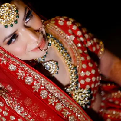 A stunning high-angle shot of the bride in her traditional red lehenga. This artistic portrait captures her beauty and the richness of her attire.