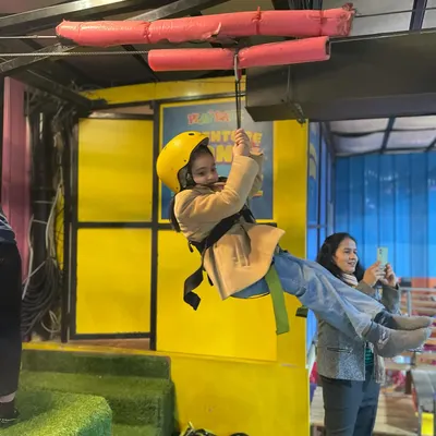 Our indoor zip-line is a huge hit with adventurous kids. Here, a young guest gets ready to fly across the play area, fully secured in a safety harness and helmet.