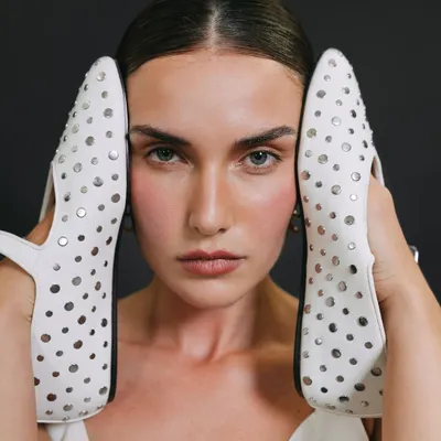 A creative and unconventional beauty shot for a model's portfolio, using a pair of white studded shoes to frame the face.