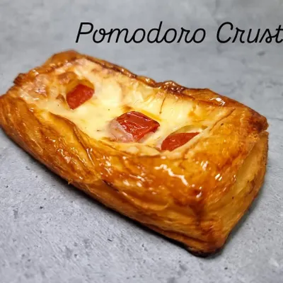 Introducing my Pomodoro Crust, a savory twist on a classic pastry. It features a flaky, buttery base topped with a creamy cheese sauce and sweet cherry tomatoes, baked until golden and delicious.
