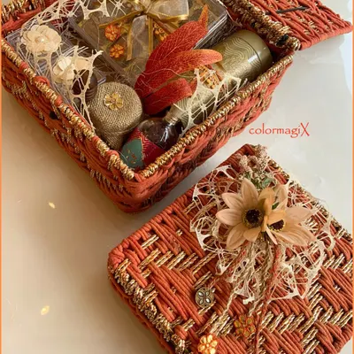 Our customizable jute hampers are a blend of eco-luxury and personal style. This orange woven box is filled with treats and adorned with a delicate flower, showcasing a rustic yet chic aesthetic.