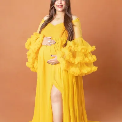 Our vibrant yellow gown with dramatic ruffled sleeves is a showstopper. It’s perfect for moms who want a bold and cheerful look for their studio maternity photos.
