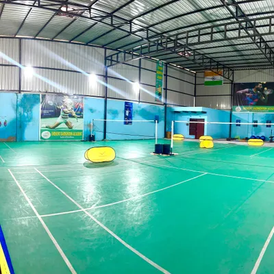 A full view of our indoor facility, showcasing multiple green synthetic courts ready for play, with clear markings and ample space.