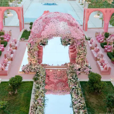 An aerial view of the 'Echoes of Pink' wedding in Doha. The entire space, from the architectural arches to the seating, was designed in monochromatic shades of pink, creating a stunning visual against the poolside venue. The floral mandap stands as the beautiful centerpiece.
