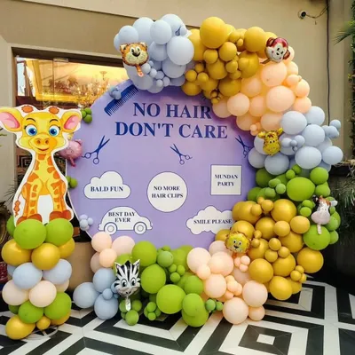 A fun and playful "No Hair Don't Care" theme for a Mundan ceremony. This setup features a custom backdrop, a vibrant pastel balloon arch, and adorable jungle animal cutouts like a giraffe and zebra.