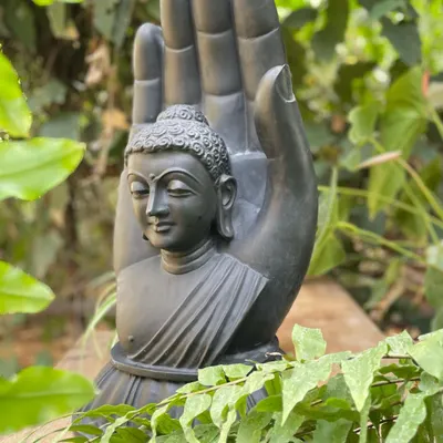 This 'Wisher of good things' is a beautifully crafted black marble statue of an ashirwad hastha (blessing hand) with a Buddha bust, ideal for a garden or indoor zen space.