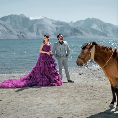 A breathtaking portrait at Pangong Lake in Leh. The bride's magnificent purple gown stands out against the serene water and stark mountains, creating a scene of unparalleled scale and beauty.