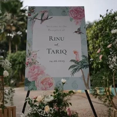 A beautifully designed welcome sign for a reception, featuring a custom illustration of the couple's names, date, and delicate floral artwork that matches the event's theme.