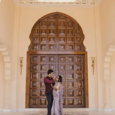 A beautiful couple portrait in front of a grand wooden door at Anantara, Jaipur. The royal architecture of Rajasthan provides an unparalleled backdrop for wedding photography.