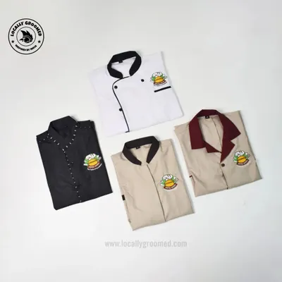 A collection of custom-made uniforms for hotel and restaurant staff. This image displays a chef's coat and different styles of service shirts, all featuring the same embroidered logo for a cohesive team appearance.