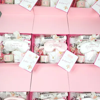A bird's-eye view of a bulk order of my signature pink bridesmaid proposal boxes. Each one is filled with curated goodies like eye masks, scented candles, and personalized notes to make every member of your bride tribe feel special.