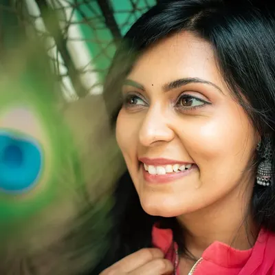 An artistic portrait using a peacock feather as a prop to create an interesting foreground element. This adds a layer of creativity and intrigue.
