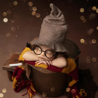 A little wizard in the making. This Harry Potter themed newborn shoot features the iconic sorting hat, glasses, and a Gryffindor scarf, complete with a magical bokeh background.