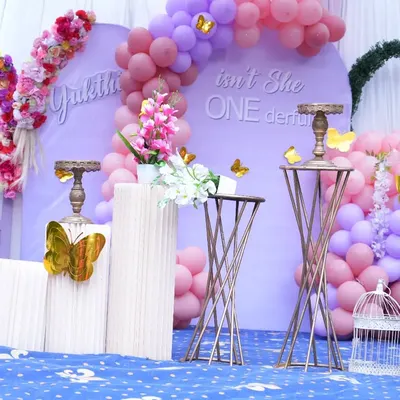 An elegant "Isn't She ONEderful" first birthday theme. This setup uses a soft lavender backdrop, pink and purple balloon arrangements, and decorative butterfly accents for a delicate and beautiful celebration.