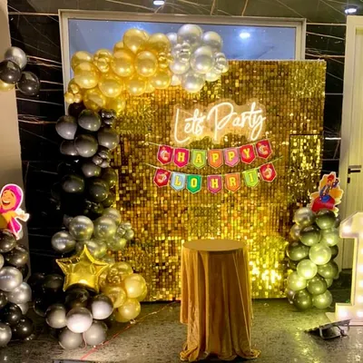 A festive Lohri celebration setup. The decor features a gold shimmer wall, a "Happy Lohri" banner, and a black and gold balloon arrangement.