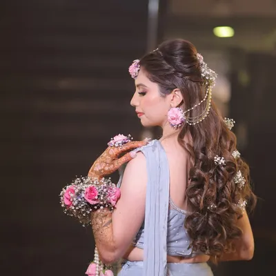 A side profile showing the elegant hairstyle with floral details that perfectly matches the mehndi theme.