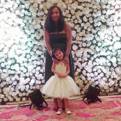 A beautiful mother-daughter moment at a wedding. I designed this little girl's white dress with a full tulle skirt and detailed bodice to make her feel as special as the occasion.