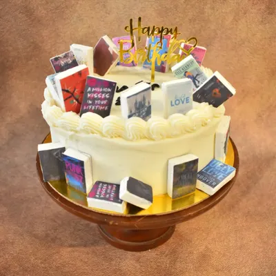 A book lover's dream cake. This cake is decorated with numerous miniature, edible book covers from popular authors and series, making it a perfect "Chapter 20" birthday celebration for a reader.
