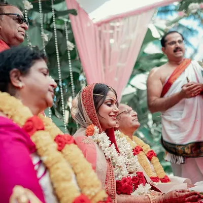 A candid shot of a bride smiling during her wedding ceremony, surrounded by her proud parents. We focus on capturing the heartfelt emotions of not just the couple, but their families as well.