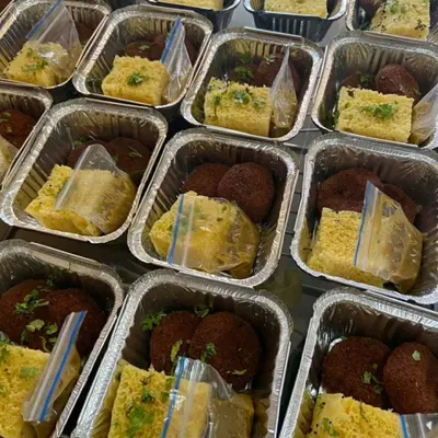 A look at a large order of 500 snack boxes being prepared for an NGO event. Each foil container is packed with fresh dhokla and veg cutlets, showing our capability to handle high-volume orders efficiently.