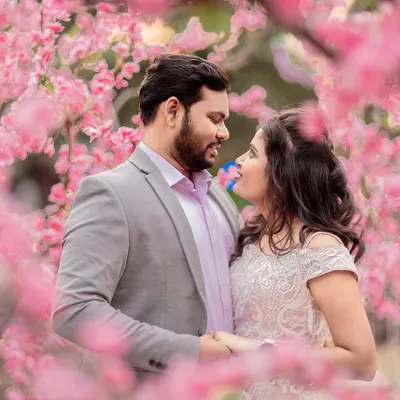 A romantic close-up of a couple surrounded by beautiful pink blossoms. This natural setting provides a soft and dreamy backdrop for an engagement portrait.