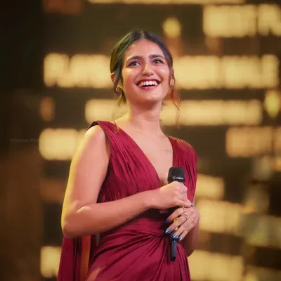 A candid shot of actress Priya P. Varrier smiling brightly while on stage at an awards show. Capturing genuine moments like this is my specialty, even in high-pressure event environments.