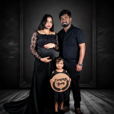 A dramatic studio maternity photo featuring the whole family. Using props like the 'Coming Soon' sign adds a lovely narrative touch to your pregnancy announcement.