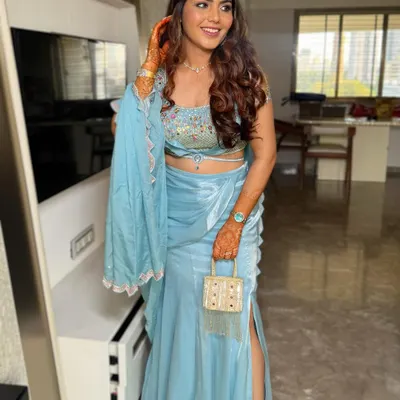 A full view of this stunning party look. The half-up hairstyle with voluminous waves perfectly complements the modern blue lehenga, making it ideal for a wedding guest or bridesmaid.