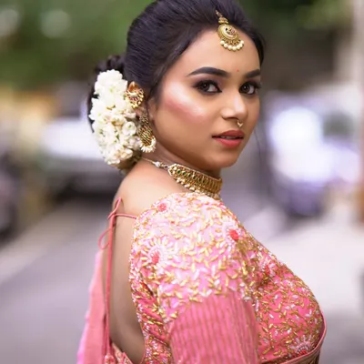 A side view of a classic bridal bun, showing how the fresh jasmine flowers are neatly arranged. This hairstyle is perfect for showcasing an ornate blouse and heavy jewelry.