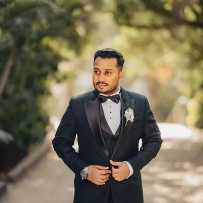 A classic portrait of the groom in his tuxedo. This shot captures his sharp attire and a confident look, set against a natural outdoor backdrop.
