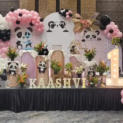 This popular Panda theme is perfect for a first birthday. The setup features a custom backdrop with cute panda illustrations, pink and black balloons, and a light-up number '1'.
